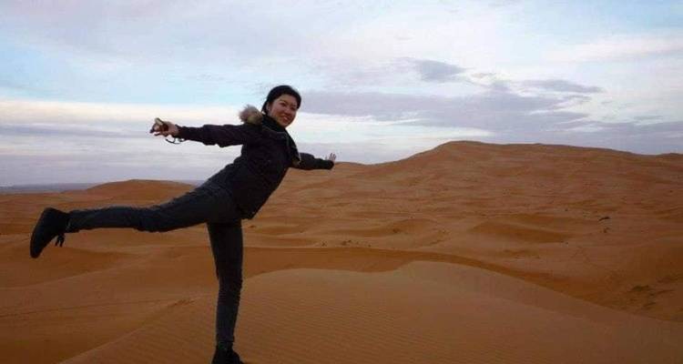Persona posando en un desierto con dunas de arena ondulantes.