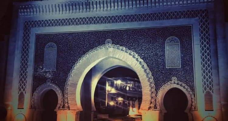 Vista nocturna de una puerta ornamentada con diseños intrincados.