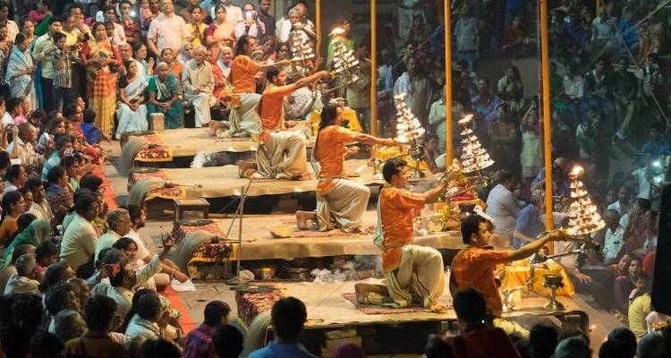 Aarti ceremony at the riverbank with participants holding lamps.