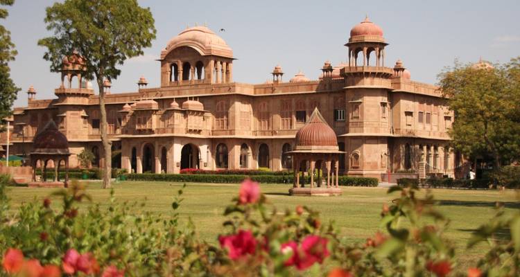 Een groots erfgoedgebouw omringd door een goed onderhouden tuin.