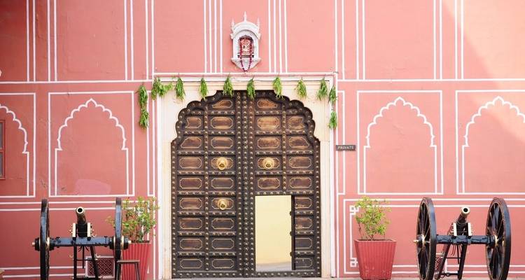 Ornately decorated door with cannons on each side in a courtyard.