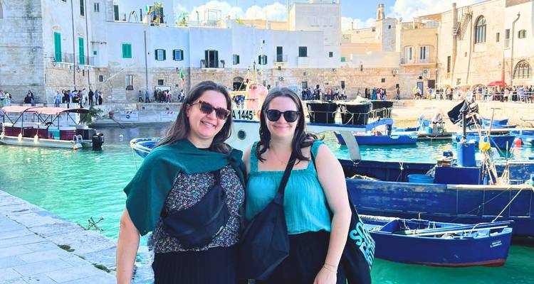 Deux femmes posant près d'un port avec de petits bateaux.