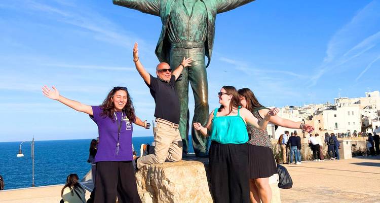 Groupe posant avec une sculpture près de la mer.