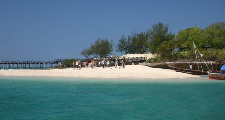 Beachfront view with tourists and traditional boats.