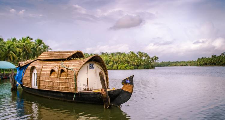 Traditionele woonboot op een kalme rivier omgeven door weelderige begroeiing.