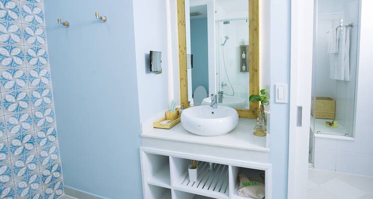 Sauberes und schlichtes Badezimmer mit rundem Waschbecken und Spiegel.