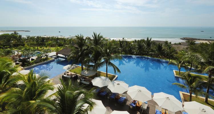 Großer Pool und Resort mit Blick auf das Meer unter klarem Himmel.