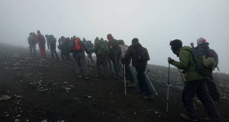 Wanderer, die bei bewölktem Wetter einen steinigen Bergpfad hinaufgehen.