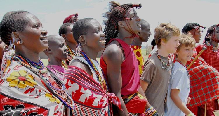 Eine Gruppe von Menschen in traditioneller Kleidung und Touristen versammelt im Freien.