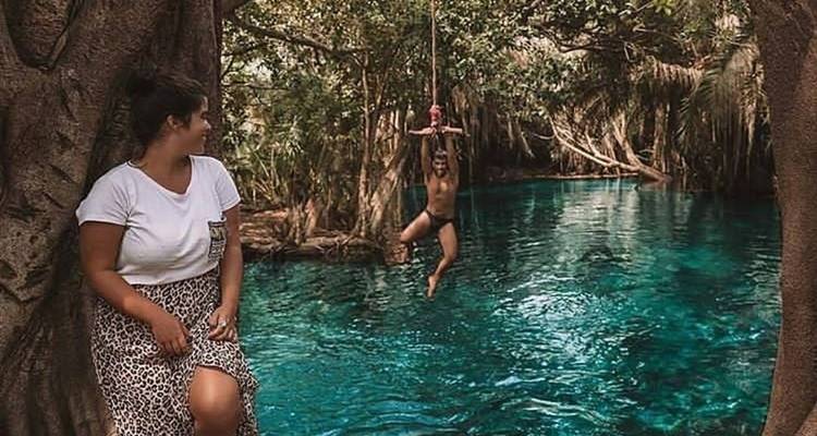 Menschen, die ein Schwimmloch genießen, das von üppigem Grün umgeben ist.