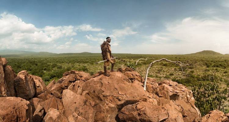 Une personne debout sur des rochers surplombant un vaste paysage.