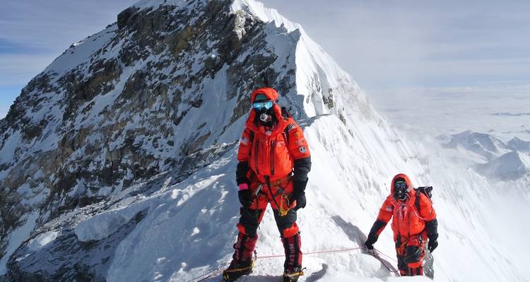 Bergsteiger auf einem verschneiten Berggipfel mit Ausrüstung.