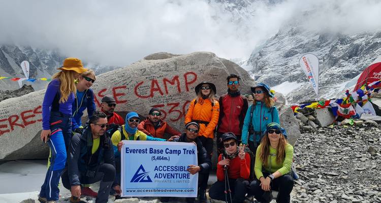 Wanderer vor dem Everest-Basislager-Felsen mit einem Banner.