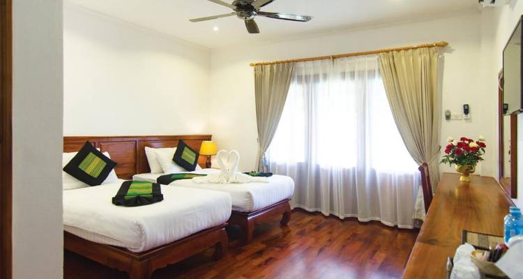 Eenvoudige hotelkamer met twee eenpersoonsbedden en traditionele inrichting.