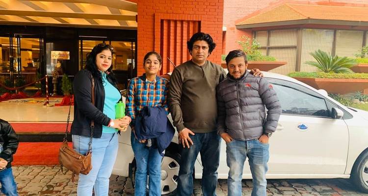 Familiengruppe posiert vor einem Auto und Backsteingebäude.