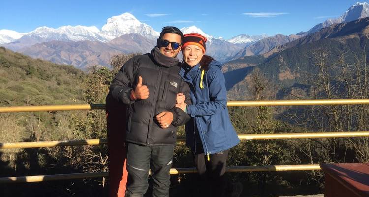 Zwei Personen posieren vor einer Berglandschaft mit schneebedeckten Gipfeln.