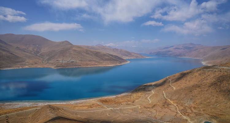 Vista panorámica de un lago azul en una zona montañosa bajo cielos despejados.