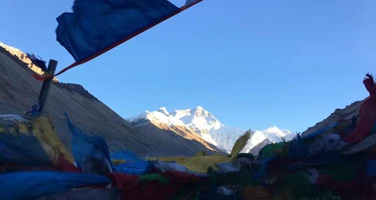 Vista de montaña con banderas de oración en primer plano contra un cielo despejado.