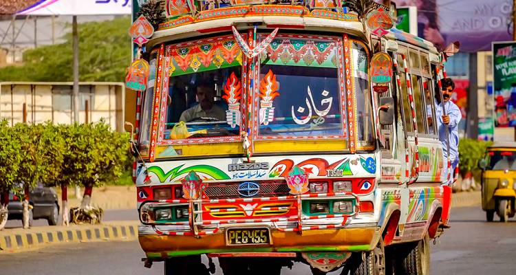 Un autobús colorido con diseños intrincados moviéndose por una carretera.