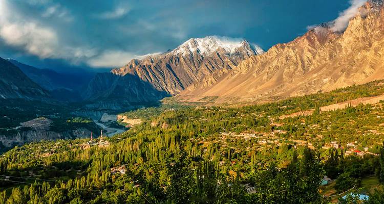 Valle pintoresco con exuberante vegetación y altas montañas bajo cielos dramáticos.