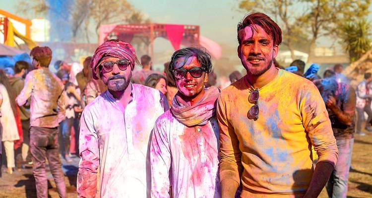 People covered in colorful powders enjoying a festival outdoors.