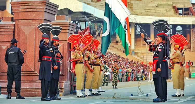 Lever de drapeau cérémoniel à la frontière indo-pakistanaise avec des gardes en uniforme et des spectateurs.