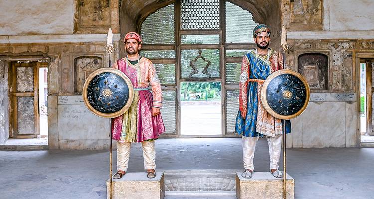 Deux hommes en tenue traditionnelle moghole à l'intérieur d'un bâtiment ancien.