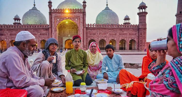 Famille savourant un repas devant la mosquée Badshahi à Lahore.