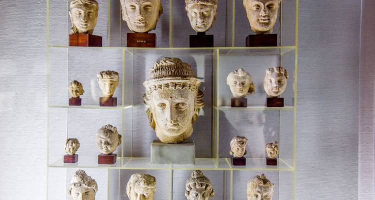 Collection d'artefacts en pierre anciens et de sculptures exposés dans un musée.