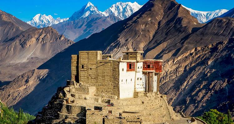 Fuerte histórico ubicado en una colina con montañas al fondo.