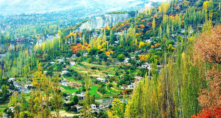 Pueblo colorido anidado en un valle verde exuberante con árboles y terrazas.