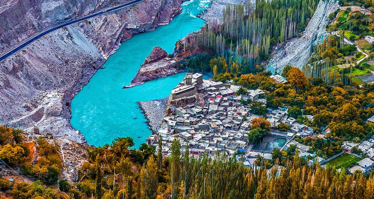 Pintoresco pueblo enclavado junto a un río turquesa con follaje otoñal.
