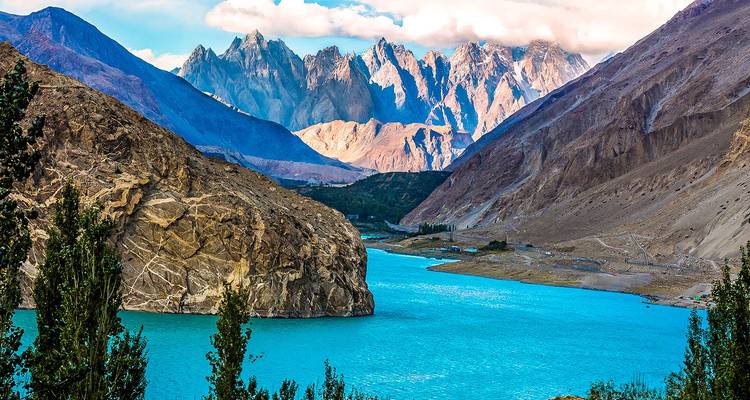 A vibrant blue lake surrounded by mountains under a clear sky.