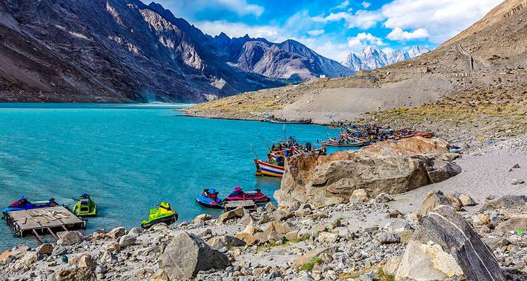 A lake with boats and jet skis near a mountainous landscape.