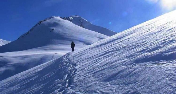 Persoon die trekt over een besneeuwde bergachtige pad.