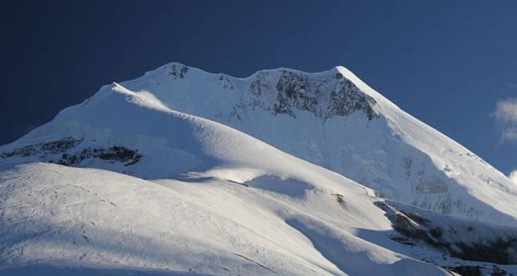 Besneeuwde bergtop onder een strakblauwe hemel.