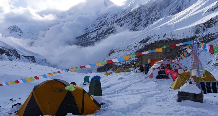 Kampeerterrein met tenten in een besneeuwde bergomgeving.