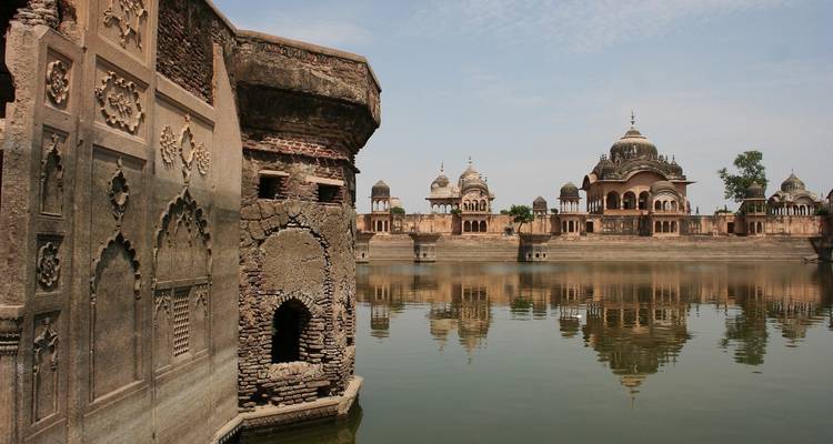 Historische Steingebäude spiegeln sich in einem ruhigen Teich wider.