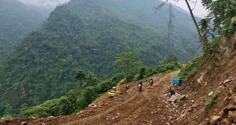 Motorrijders op een modderig bospad met bouwmateriaal.