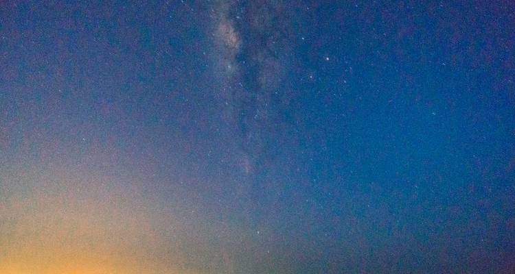 Starry night sky with Milky Way visible over horizon.
