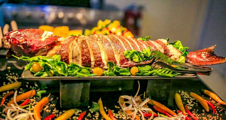 Gourmet dish featuring a whole roasted fish with vibrant vegetables.