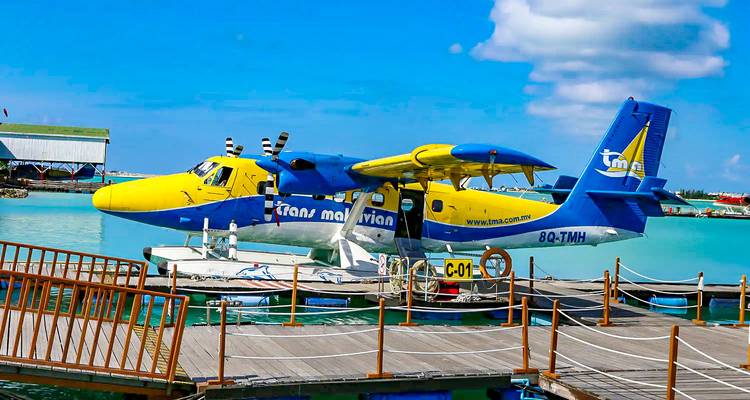 Seaplane docked at a pier over clear turquoise waters.