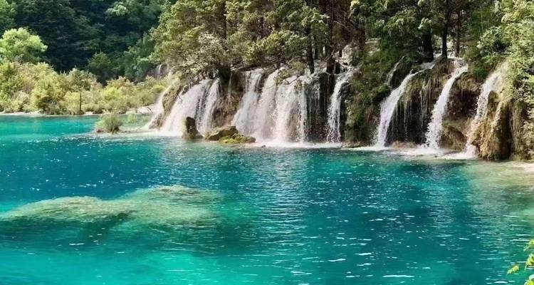 Helder turquoise meer met watervalletjes en groen gebladerte.