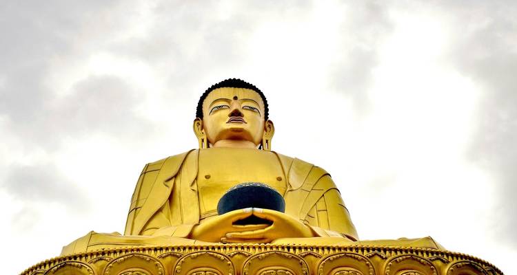 Gouden standbeeld van Boeddha tegen een heldere hemel.