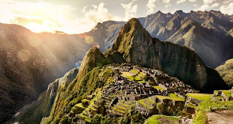 Iconisch uitzicht op de Machu Picchu ruïnes gelegen op een weelderige bergkam bij zonsopgang.