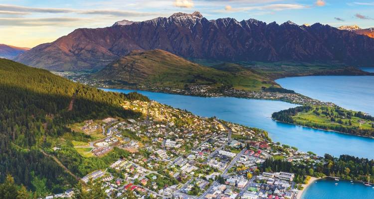 Luftaufnahme von Queenstown, eingebettet zwischen dem See und einer dramatischen, schneebedeckten Bergkette.
