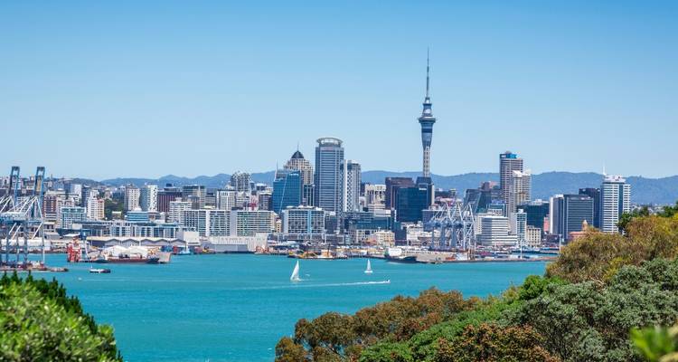 Strahlend blauer Tagesblick auf die Skyline von Auckland über türkisfarbene Hafengewässer mit Segelbooten.