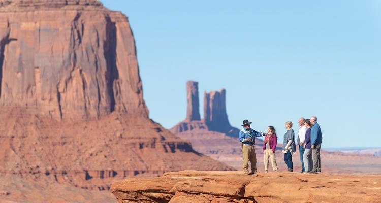 Grupo de personas en el borde de un acantilado con vista al Valle de los Monumentos.
