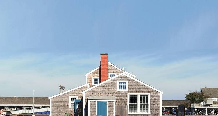 A traditional wooden house with a blue door against a clear sky.