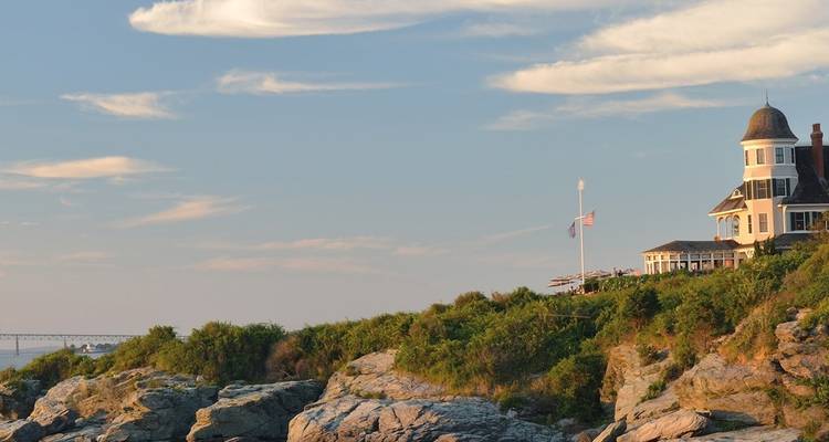 Coastal landscape with a large house sitting on rocky cliffs.